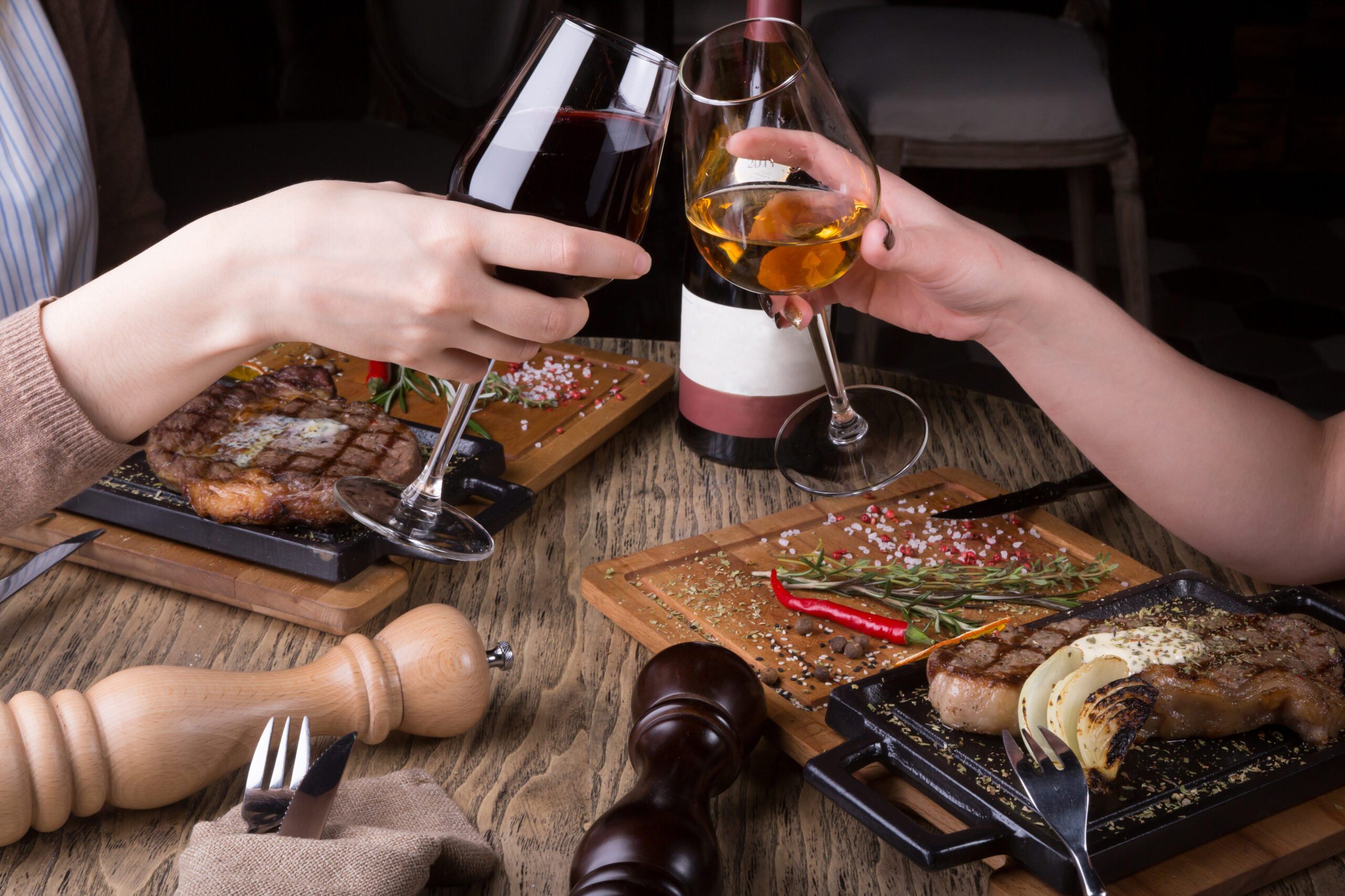 Woman's hands cheering with glasses of white and red wine