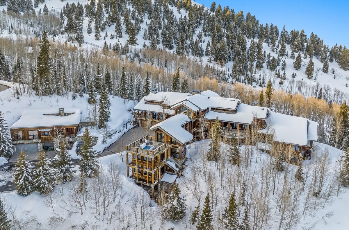 Talus RIdge, a ski in ski out vacation rental in park city. the view of the home is slopeside, there is a large snow covered mountain in the back. the home is multiple stories with a view of the deck