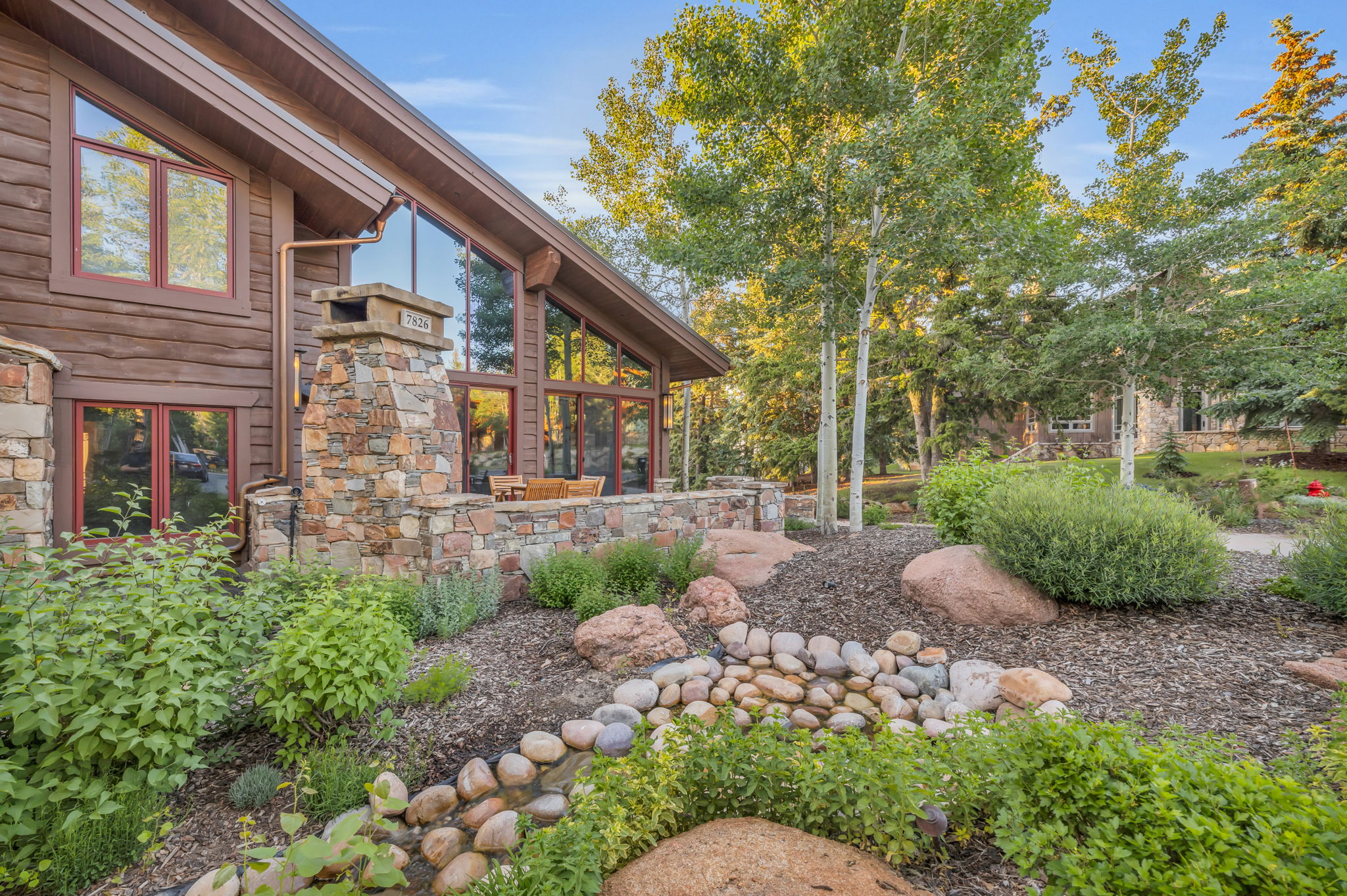 A luxury home exterior in park city with manicured landscaping and a wooded view