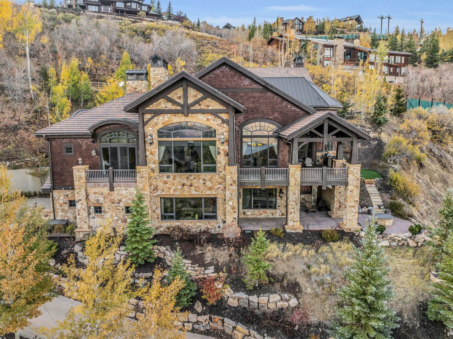 overhead view of a home covered with stunning stonework along the mountain side at Deer Crest in Deer Valley with fall colors and ski runs in the background