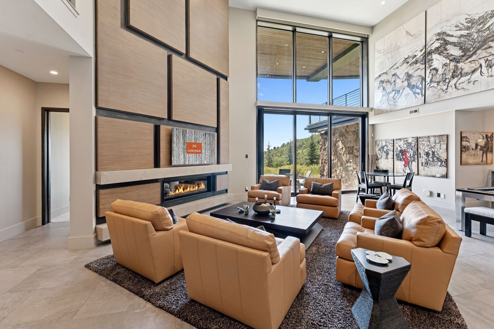 a cozy modern living space overlooking the ski runs of deer valley. there is a fireplace and overstuffed leather couches