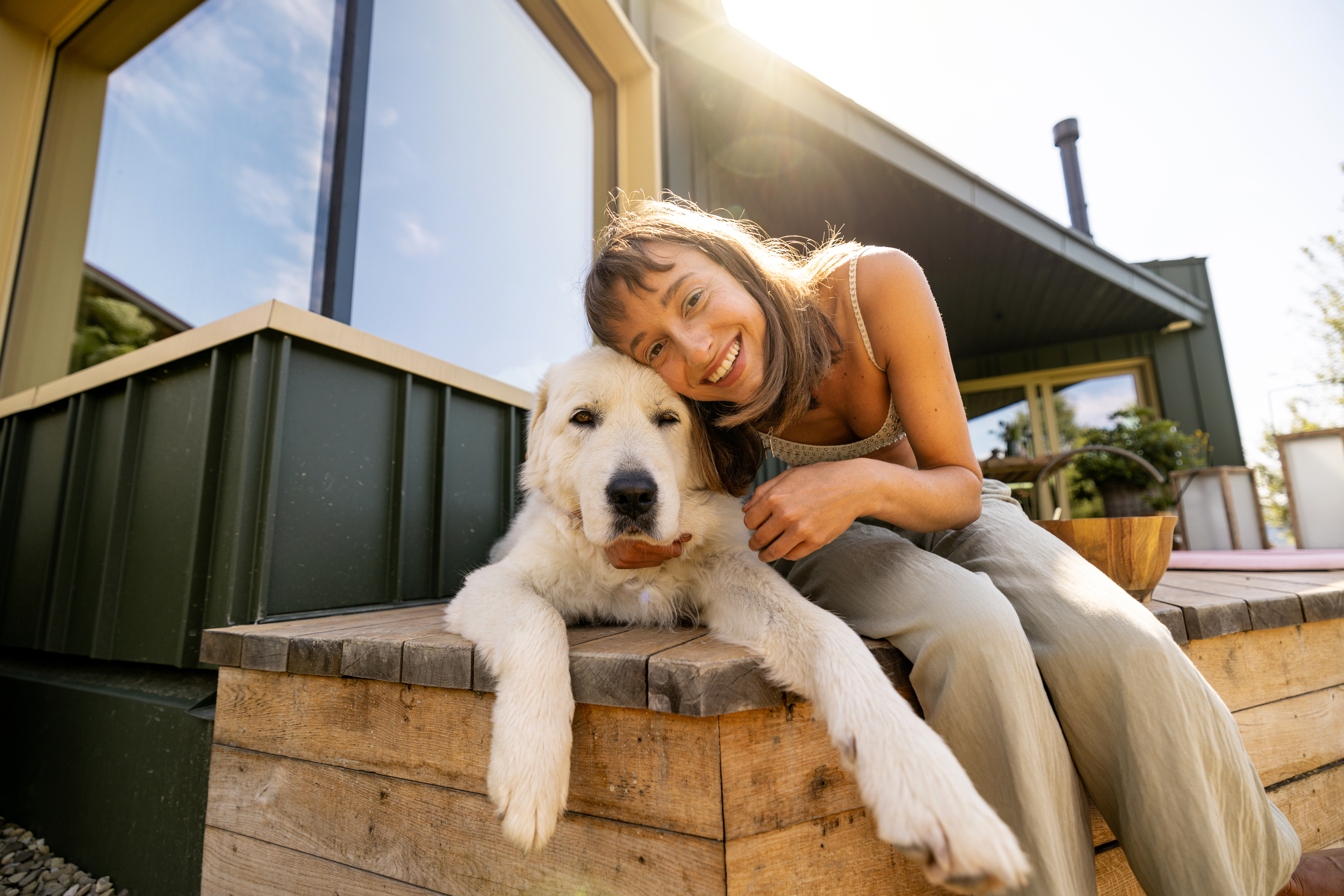 A joyful moment shared between a woman and her dog, capturing the essence of happiness and companionship. The sunlight gently illuminates their faces, highlighting the warmth of their bond