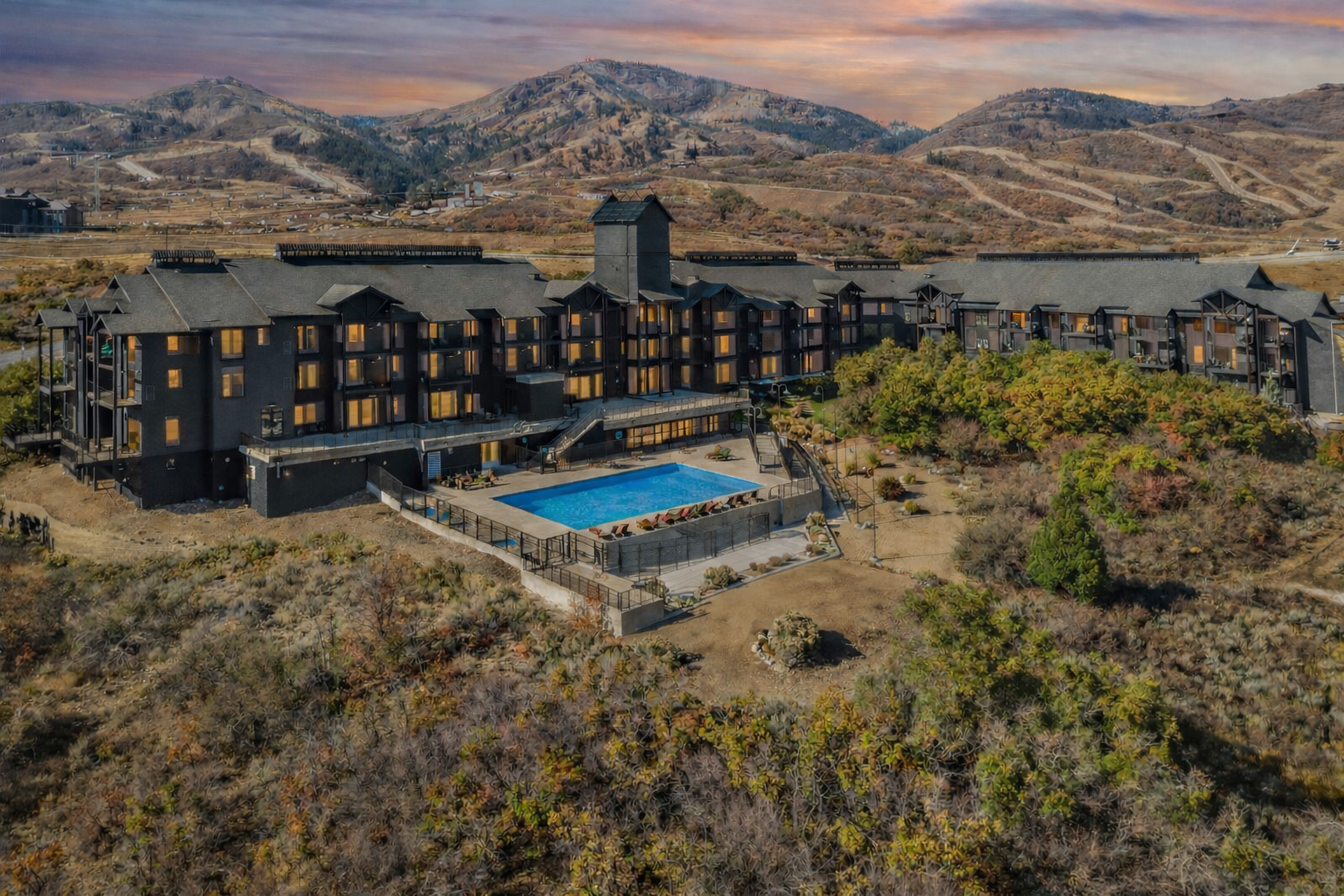 The Mason at Deer Valley east at sunset with a bright aqua pool visible and the mountains of deer valley in the background