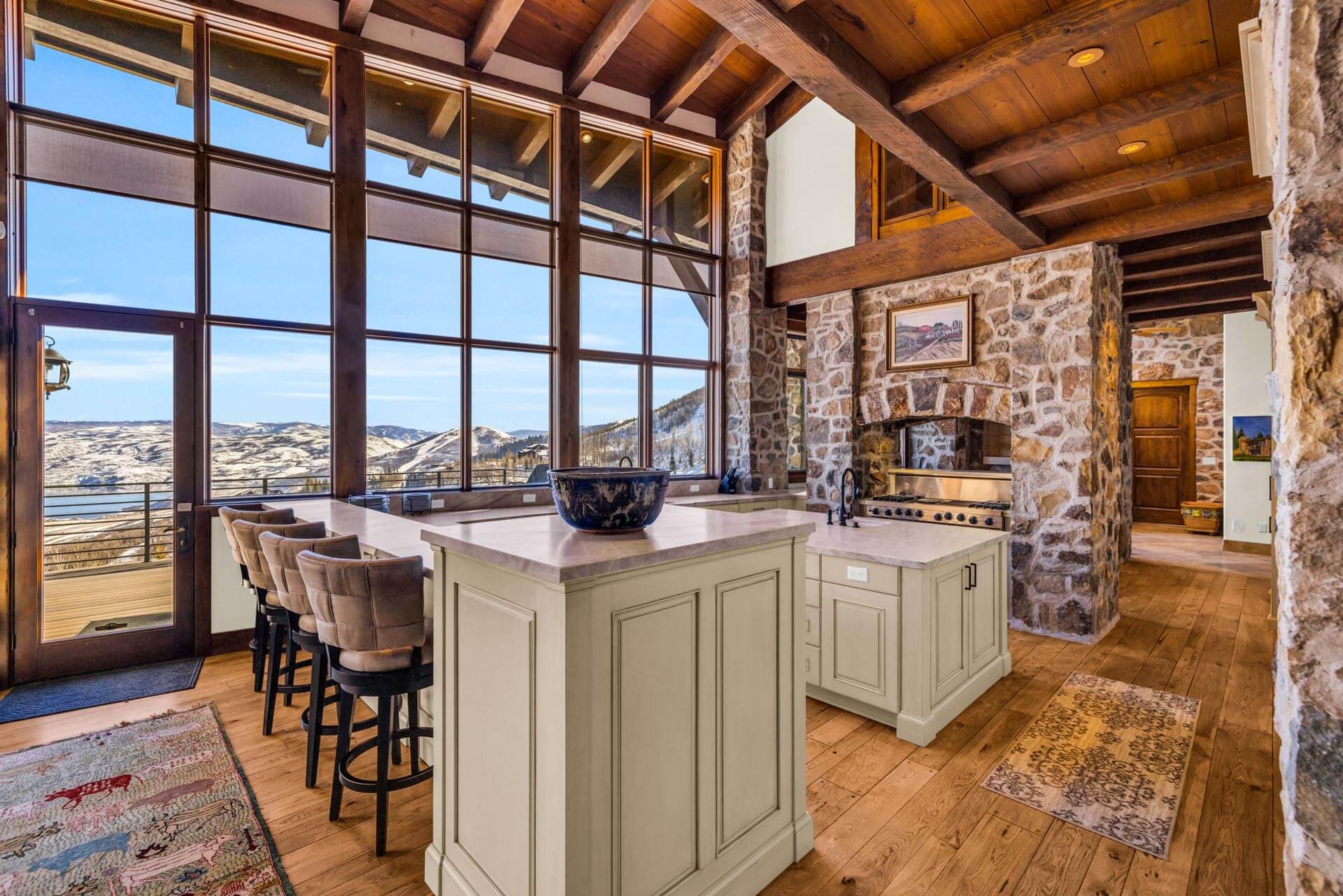A view of the slopes from the inside of a ski in, ski out luxury vacation rental with a large stone fireplace and spacious dining area. Discover luxury Deer Valley ski-in ski-out vacation rentals from Luxe Haus. Enjoy world-class skiing and top-notch amenities for your perfect getaway.