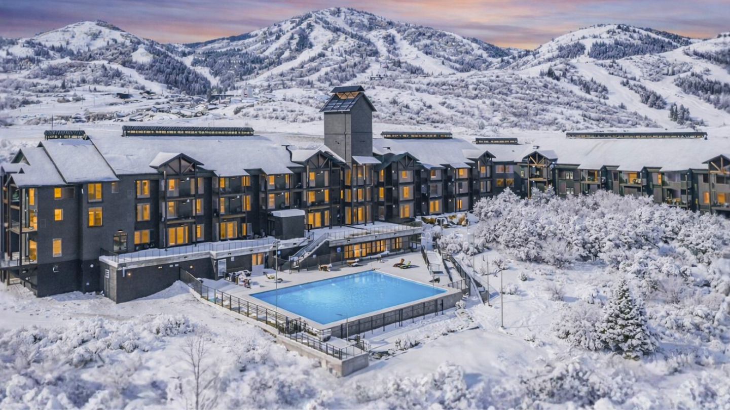 The Mason at sundown in Deer Valley East with large pool and hot tubs visible and the slopes of deer valley in the background